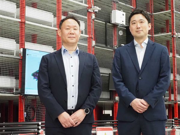 インタビューに対応いただいた株式会社アルプス物流 保管BU 部長 野殿征範氏（左）と 同社経営企画部 経営企画課 課長 渡邊真広氏（右）。大栄倉庫導入のラピュタASRS前で。